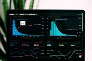 Uma tela de computador exibe tabelas e gráficos de análise do site, mostrando dados sobre tempo de carregamento, taxa de rejeição, visualizações de página, sessões e tempo médio de sessão nos últimos sete dias.