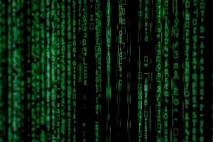 Código digital verde com símbolos e números variados exibidos em linhas verticais em um fundo preto, semelhante a um fluxo de dados de computador.