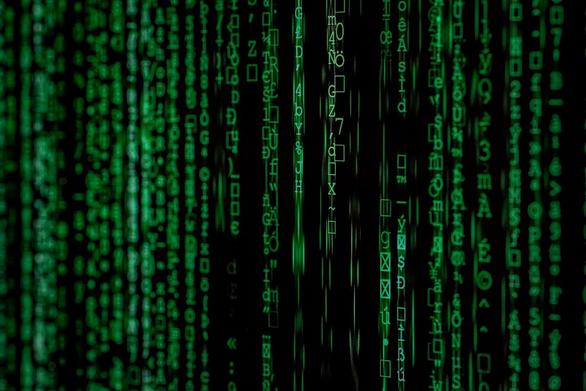 Código digital verde com símbolos e números variados exibidos em linhas verticais em um fundo preto, semelhante a um fluxo de dados de computador.